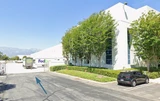 Tree-lined driveway leading to a white warehouse with a FedEx truck and parked SUV