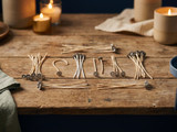 Bundles of pre-tabbed cotton candle wicks with metal base tabs on a rustic wood table, lit candles glowing behind