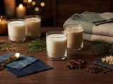 Cream candles in clear glasses on dark wood with cedar, pine, star anise, cloves, resin and a wool blanket