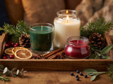 Green, cream, and red candles on a wood tray with pine, pinecones, dried orange, and cinnamon