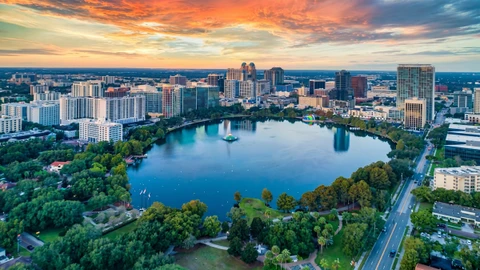 Aerial view of the Orlando skyline around a lake with a fountain at sunset