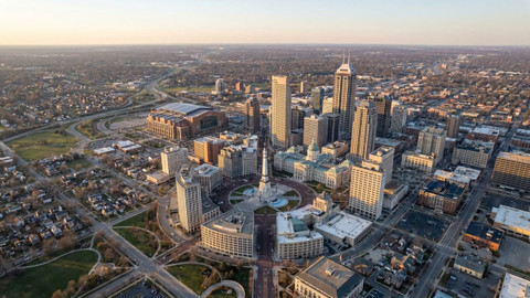 aerial view of downtown Indianapolis at golden hour, centered on the circular Soldiers and Sailors Monument plaza