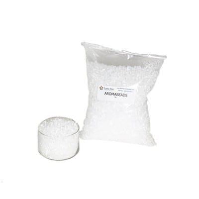 Clear plastic bag of white aroma beads labeled Aromabeads beside a small glass dish of beads