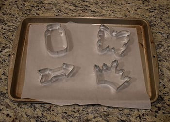 Mason jar, butterfly, arrow, and crown metal cookie cutters on a parchment-lined baking sheet