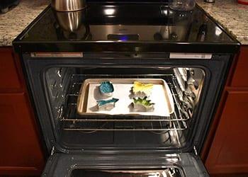 Baking sheet of bead-filled cookie cutters on the rack inside an open oven