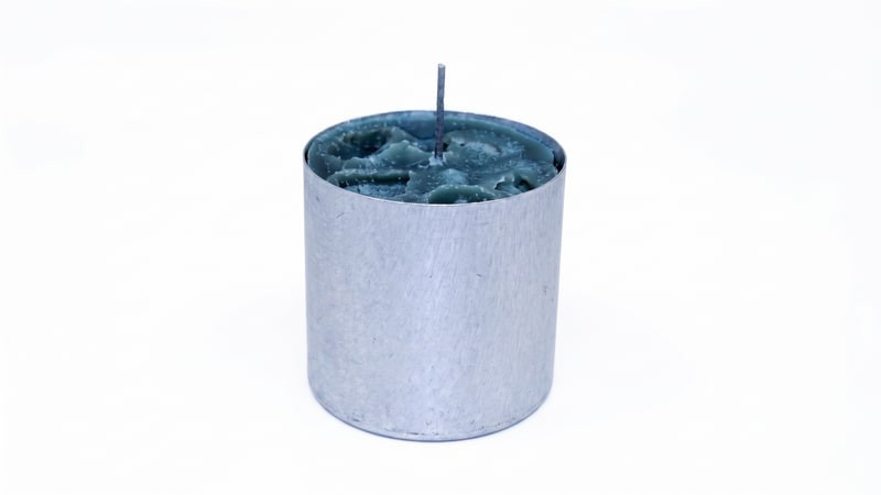 Teal ice candle with upright wick set inside an upright aluminum pillar mold