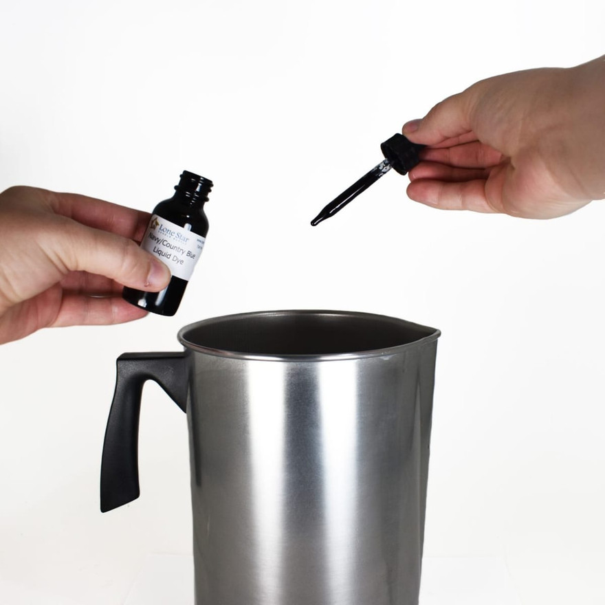 Hands holding a Lone Star Navy/Country Blue liquid dye bottle and dropper over an aluminum pouring pitcher