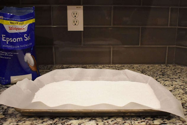 Epsom salt spread evenly on a parchment-lined sheet beside a Walgreens Epsom salt bag