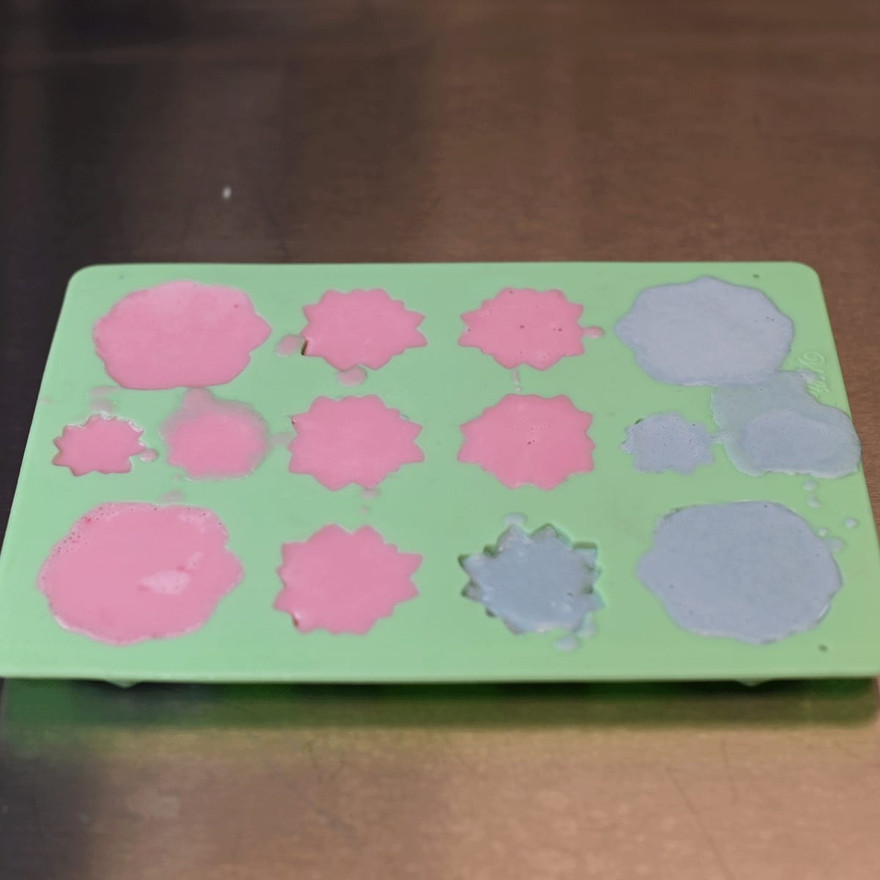 A filled succulent mold with pink and teal soap in the cavities