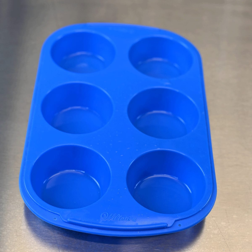 An empty blue six-cavity silicone muffin mold