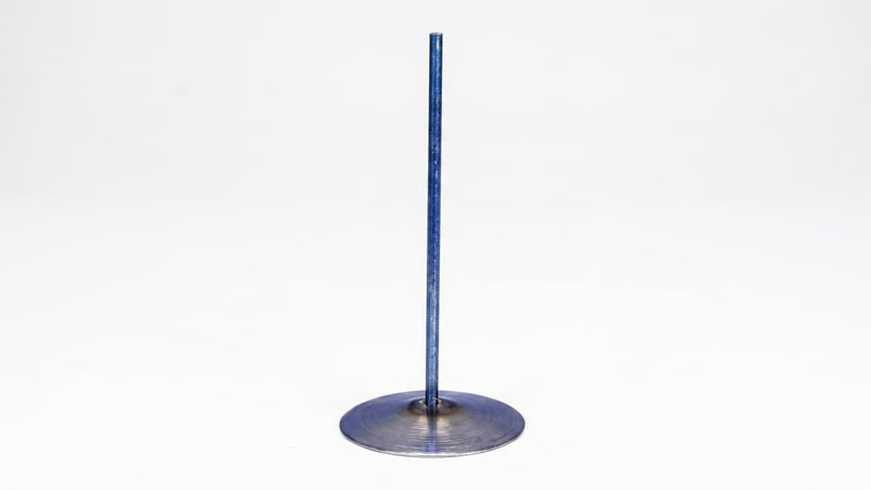 Single metal votive wick pin standing upright with a round base and tall stem