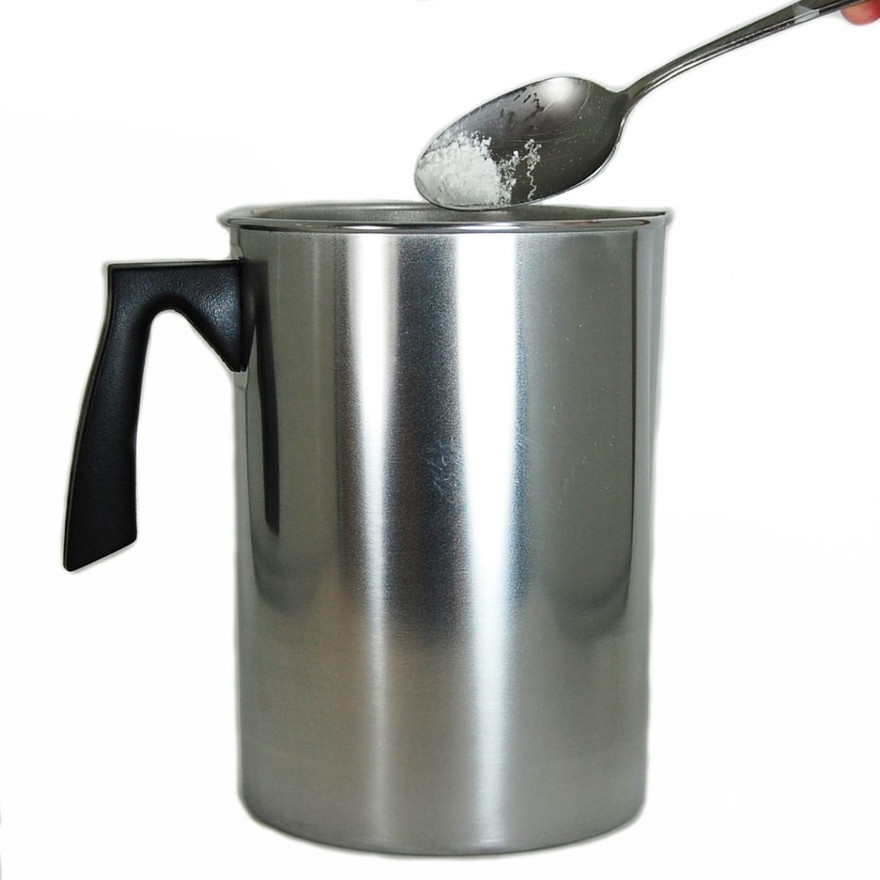 Spoonful of white powder held above the rim of an aluminum pouring pitcher